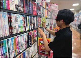 店頭で本棚に商品を並べる人物が撮影されている
